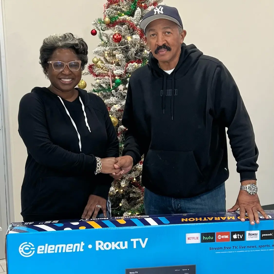 Woman and man shaking hands posing with an Element TV box