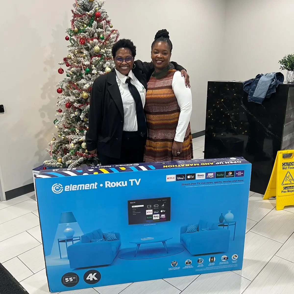 Two women hugging and posing with an Element TV box