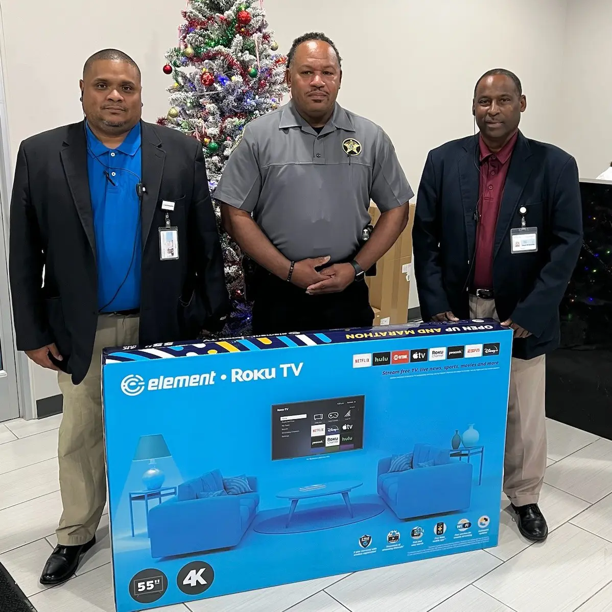 Three men posing with an Element TV box