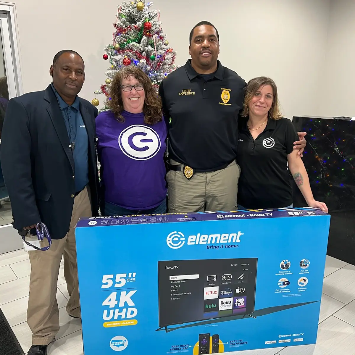 Four people posing with an Element TV box